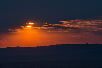 Stunning sunset over Varna suburbs  in the far distance, Bulgaria. Sun hidden behind clouds, rays passing through them. Landscape, cityscape, travel concept. Selective focus, copy space. Silhouettes. 