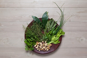 Herbs, Spices and Nuts on Dark Wood Plate, on Wooden Background – Parsley, Mint, Fennel, Thyme, Bay, Sage, Basil, Chive, Celery, Almonds, Walnuts, Pistachio