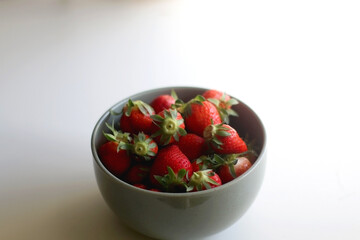 Bowl of fresh strawberries on white table. Selective focus.