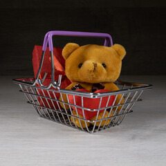A bear with a heart in his hands sits in a shopping basket.