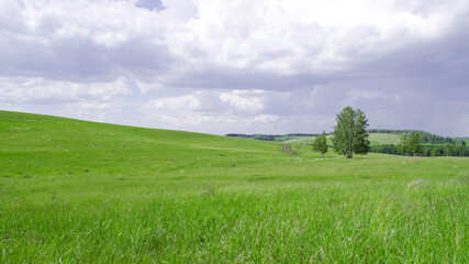 landscape a country road on the side of a green hill and the sky with dark clouds