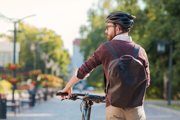 Portrait of a male commuter wearing bike helmet in a town. Safe cycling in city, bicycle commuting, active urban lifestyle image