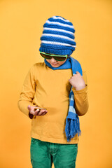 A boy with glasses in a hat and scarf looks at the compass so as not to get lost.
