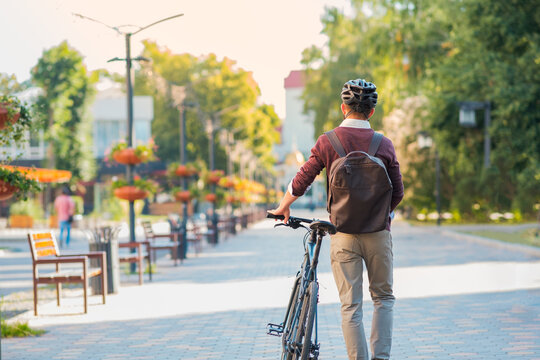 Male commuter wearing bike helmet walking away. Safe cycling in city, bicycle commuting, active urban lifestyle image