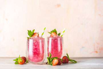 Fresh strawberry cocktail. Fresh summer cocktail with strawberry and ice cubes. Glass of strawberry soda drink on light pink background
