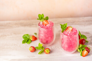Fresh strawberry cocktail. Fresh summer cocktail with strawberry and ice cubes. Glass of strawberry soda drink on light pink background