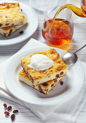 Mouth-watering cheese casserole pieces with yoghurt, vivid tea poured into a glass.