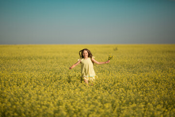 portrait of a teenage girl in a yellow dress running across the field in summer