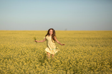 portrait of a teenage girl in a yellow dress running across the field in summer
