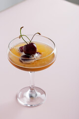minimal cocktail drink with sweet cherry in glass at pink background