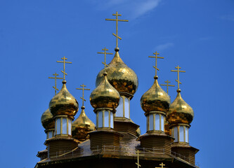 Fototapeta na wymiar Golden domes of an Orthodox church against a bright blue sky