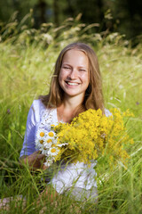 Closeup portrait of a young girl with a bouquet of wildflowers. Shallow focus.