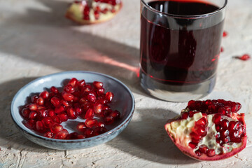 Glass of pomegranate juice on a white concrete background. Hard light, side view, selective focus.