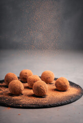 Truffles from dates in carob on a slate Board are sprinkled with carob