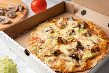 Vegetarian pizza with mushrooms near the ingredients in a cardboard box