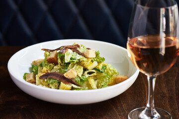 Beautiful Caesar Salad with Glass of Rose Wine in Restaurant