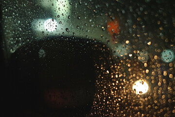 City street. Rainy night, raindrops. Vehicles, tail lights. Windshield