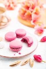 Purple macarons or macaroons cakes with cup of coffee on a white concrete background. Side view, close up, selective focus.