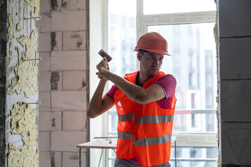 Young worker holding a hammer and a pointed chisel