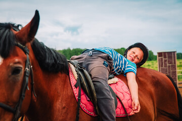 Fototapeta premium Boy horseback riding, performing exercises on horseback, horse theraphy