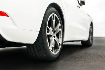 Plakat White car close up. Car wheels close up on a background of asphalt. Car tires. Car wheel close-up. for advertising