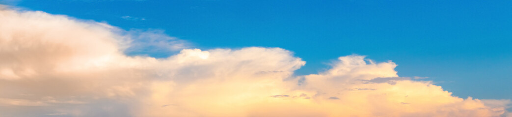 Obraz premium Panorama of blue sky with light fluffy clouds at sunset