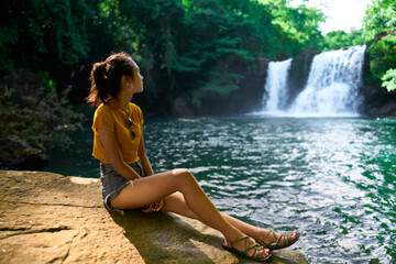 A girl looking at a waterfall in beautiful nature