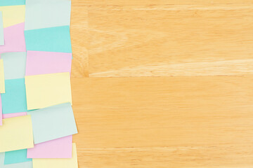 Sticky note background with multi-color notes on a wood desk