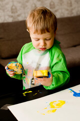 Very serious face. Toddler painting with sponge and hands.