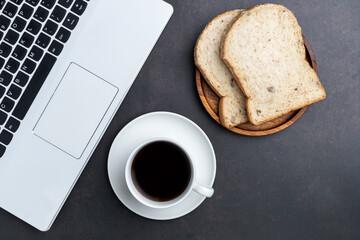 Laptop,coffee, and bread on table desk. View from above with copy space