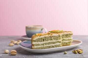 Homemade cake with milk cream and pistachio with cup of coffee on a gray and pink background. side view, selective focus.