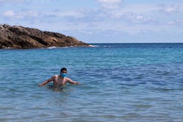 young man taking a dip in the beach with a mask