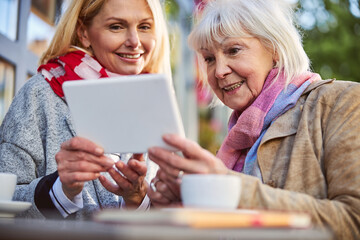 Cheerful adult females looking to the screen modern device
