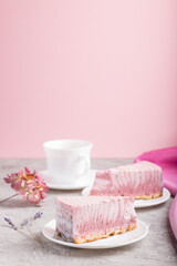 Homemade pink cheesecake with cup of coffee on a gray and pink background. side view, selective focus, copy space.
