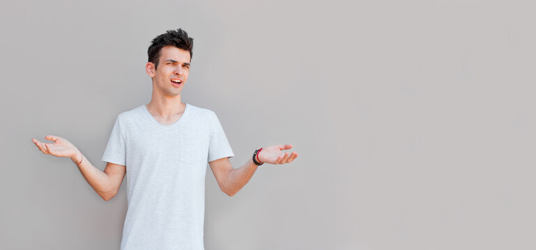Closeup portrait of dumb clueless young man, arms out asking what's the problem who cares so what, I don't know. Isolated on white background. Negative human emotion, facial expressions, attitude