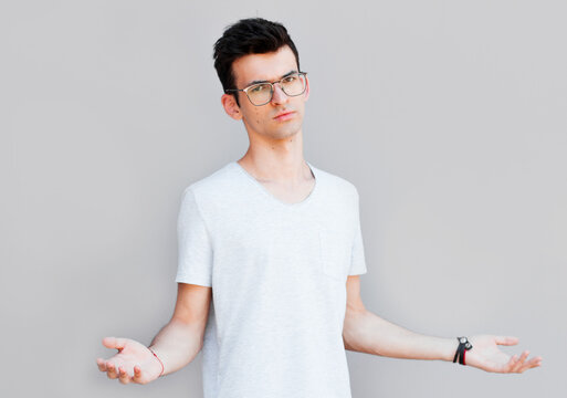 Closeup portrait of dumb clueless young man, arms out asking what's the problem who cares so what, I don't know. Isolated on white background. Negative human emotion, facial expressions, attitude