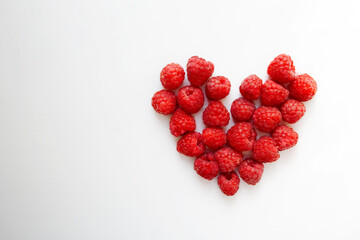 Fresh raspberries heart shaped composition isolated on white background with a copy space