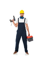 Handsome workman in uniform and hardhat holding electric screwdriver and toolbox on white background