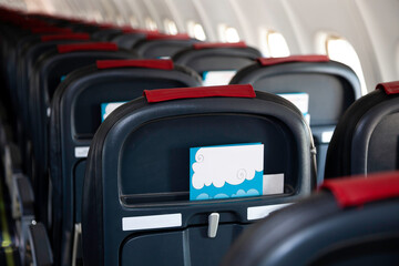 Fototapeta premium Airplane instruction, layout with place for text. Advertising brochure. Empty cabin of the plane. Soft seats for passengers, portholes. Inside a passenger plane. A seat on the plane. Copy space.