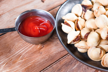 Appetizing fried dumplings in a black plate on a wooden table. Simple rustic food and snacks concept