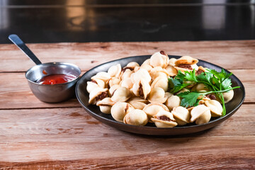 Appetizing fried dumplings in a black plate on a wooden table. Simple rustic food and snacks concept