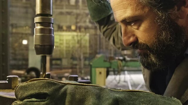 Mature jeweler working on engraving machine in workshop