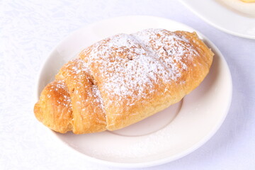 Croissant with powdered sugar on a white plate