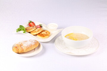 Cheesecakes, oatmeal and croissant on white background