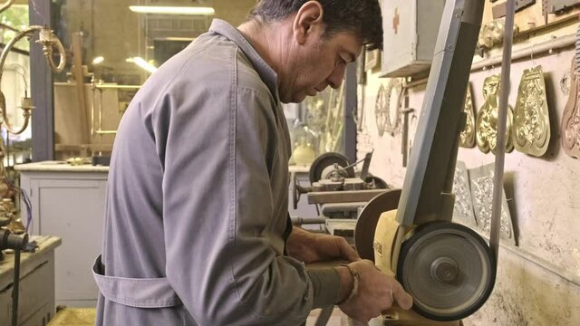 Goldsmith processing metal detail in workshop