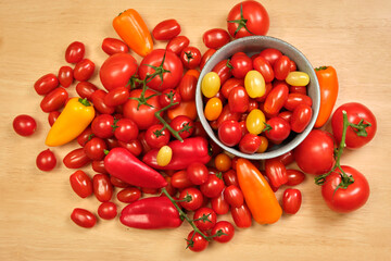 Bright yellow, red, orange tomatoes and peppers , a light blue bowl with tomatoes on a wooden background.