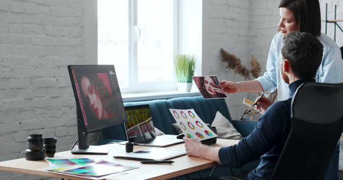 Young creative Photographer working in his Office, choosing best Footage with his Assistant. Young Talented Photographer Working in Loft Studio. Freelance Working, Modern Professions. Technology.