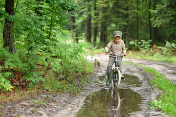 5 years old boy is having fun in the forest. The active child is riding a bicycle. Active recreation.