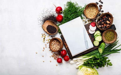 Open blank recipe book with healthy vegan ingredients for cooking and chopping board top view.