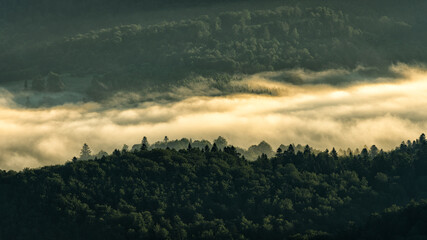 A hazy sunrise in the mountains. Mountains silhouettes and fog in the valleys. Photo from Polonina Wetlinska. Bieszczady National Park. Carpathians. Poland.